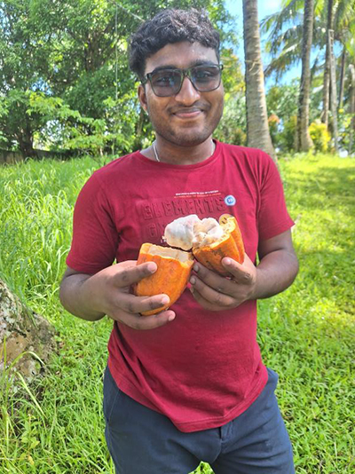 Daniel (Sri Lanka) mit Kakaofrucht in unserem Garten.