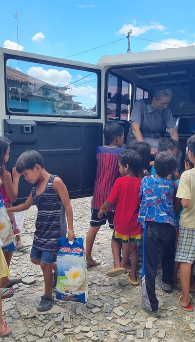 Die Kinder helfen beim Ausladen von Reis und  anderen Lebensmitteln.